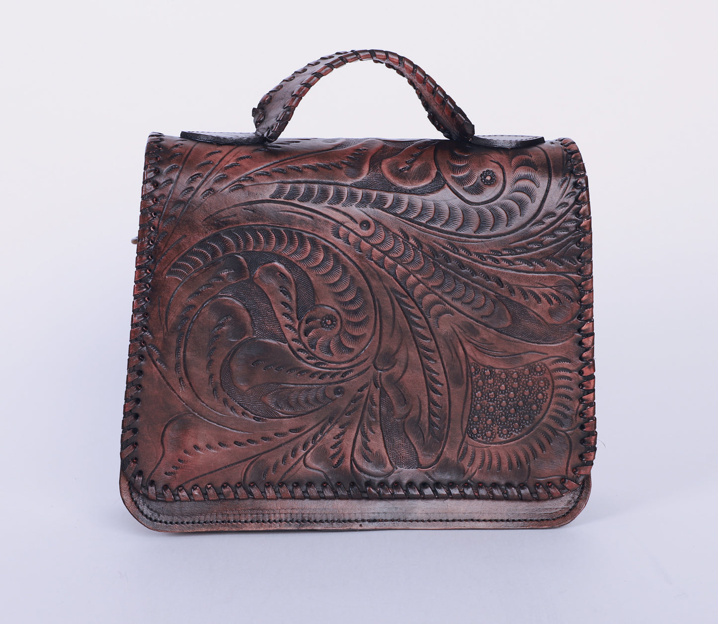 Medium-sized full leather handbag with a traditional mexican etching design on the upper flap. Braided handle on top. Fully lined with suede.  Front view in brown color.
