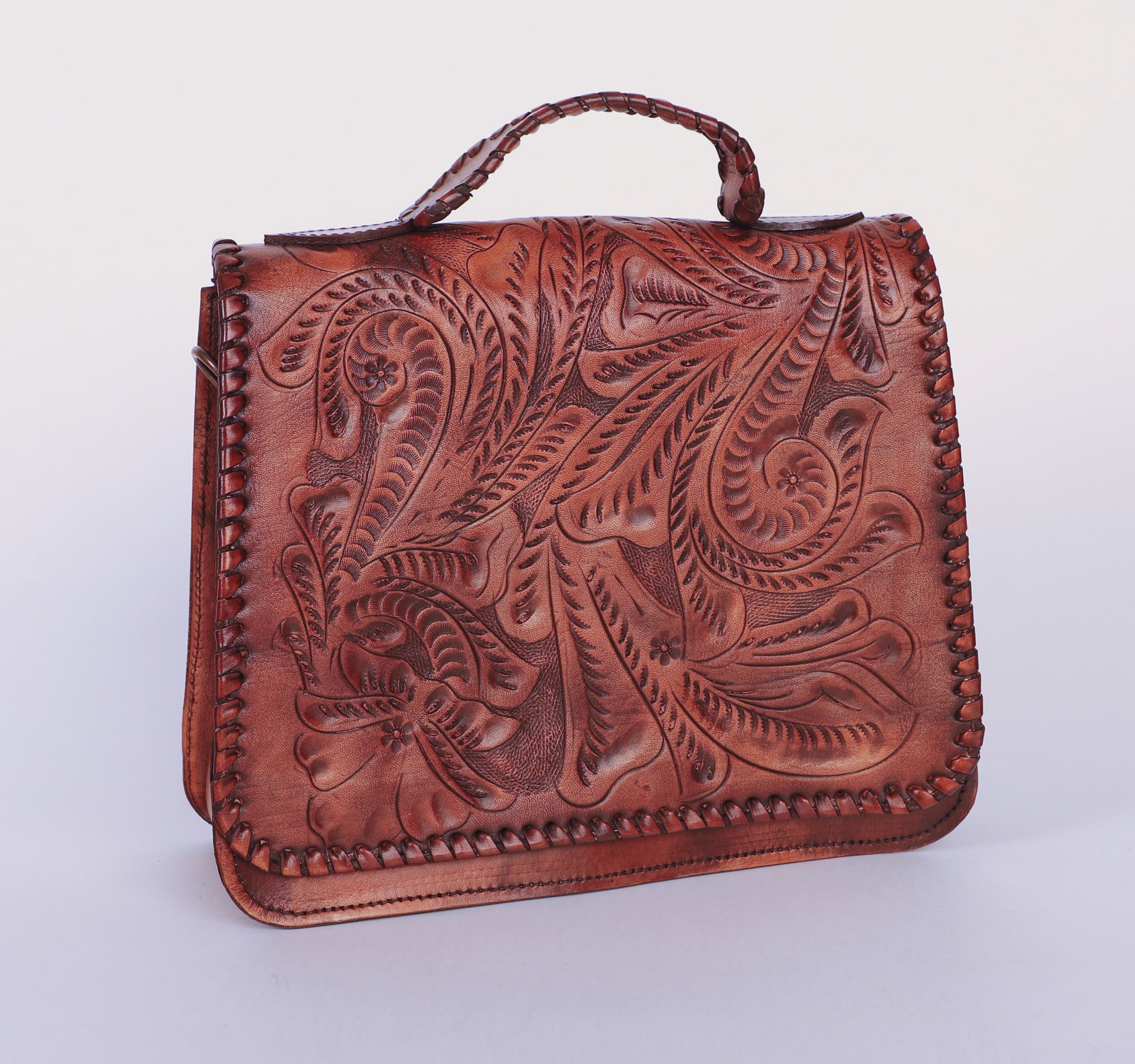 Medium-sized full leather handbag with a traditional mexican etching design on the upper flap. Braided handle on top. Fully lined with suede.  Front view in popular color camel. 