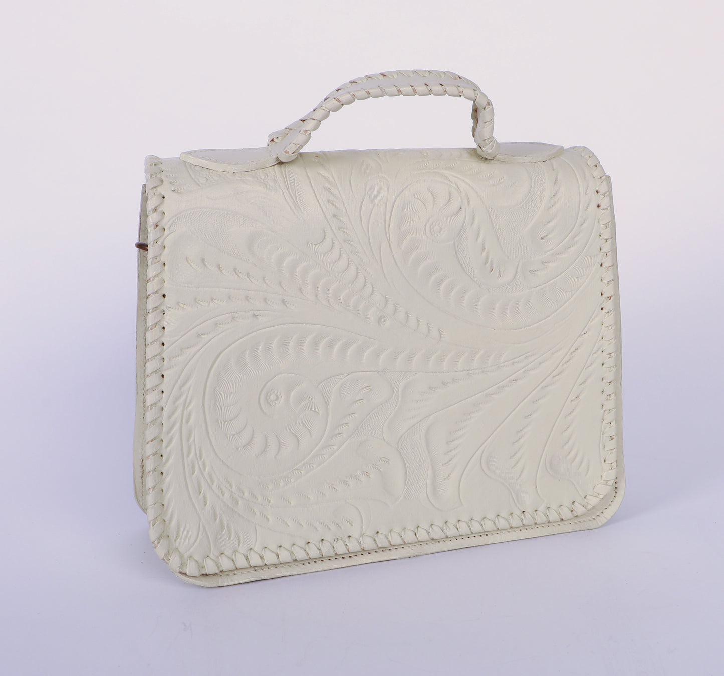 Medium-sized authentic leather handbag with a traditional mexican etching design on the upper flap. Braided handle on top. Fully lined with suede.  Front view in color white. 