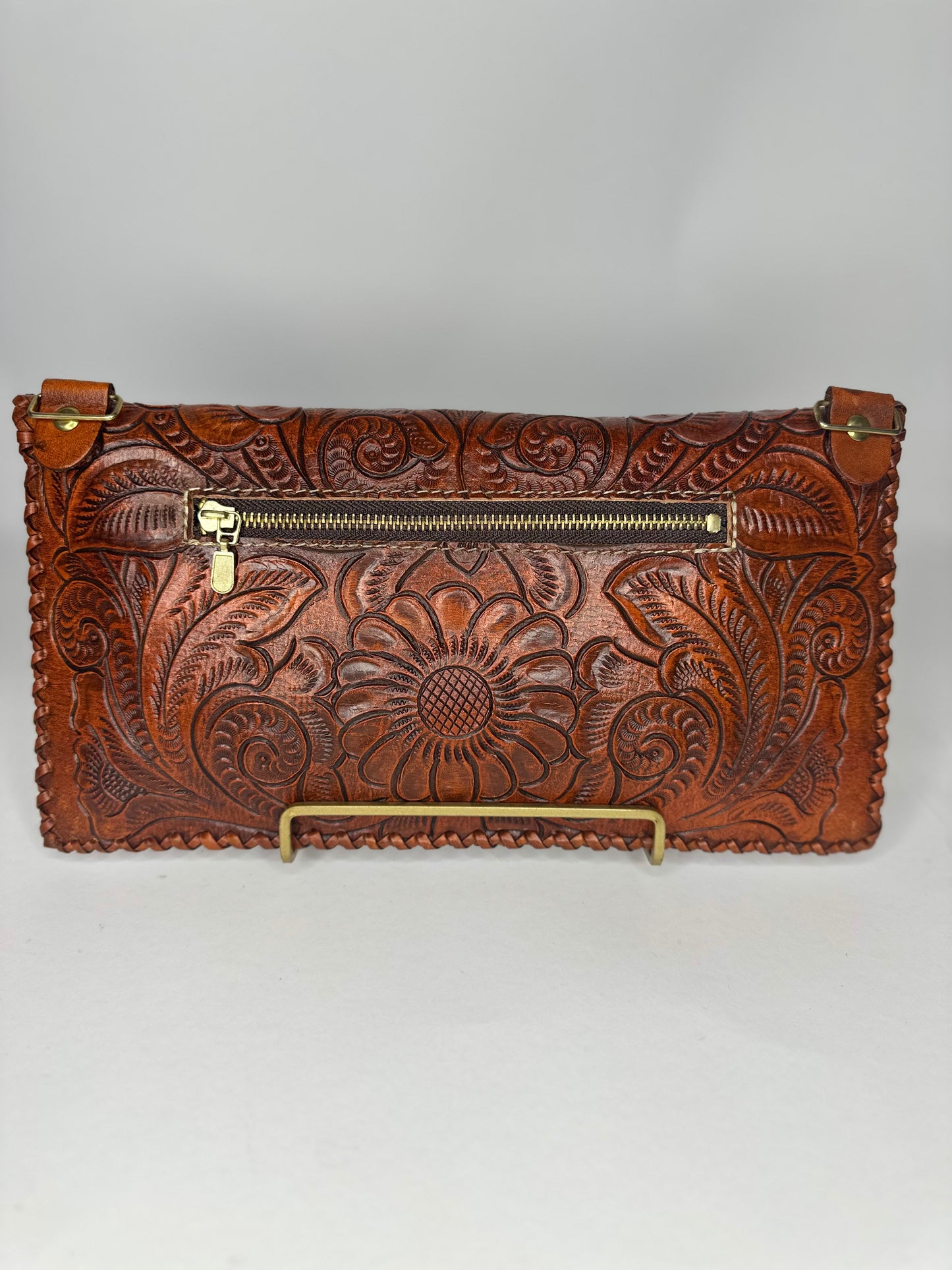 Handmade Mexican authentic leather clutch with floral design etched on top flap and back. Squared design etched on bottom half and zipper in back. color brown.