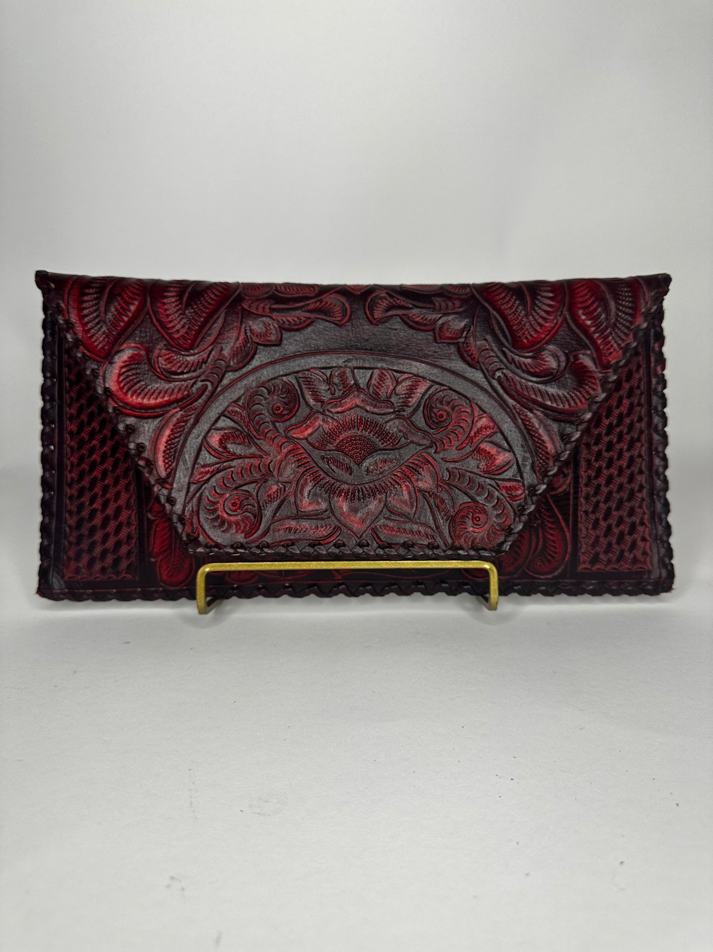 Handmade Mexican authentic leather clutch with floral design etched on top flap. Squared design etched on bottom half. Color wine red.