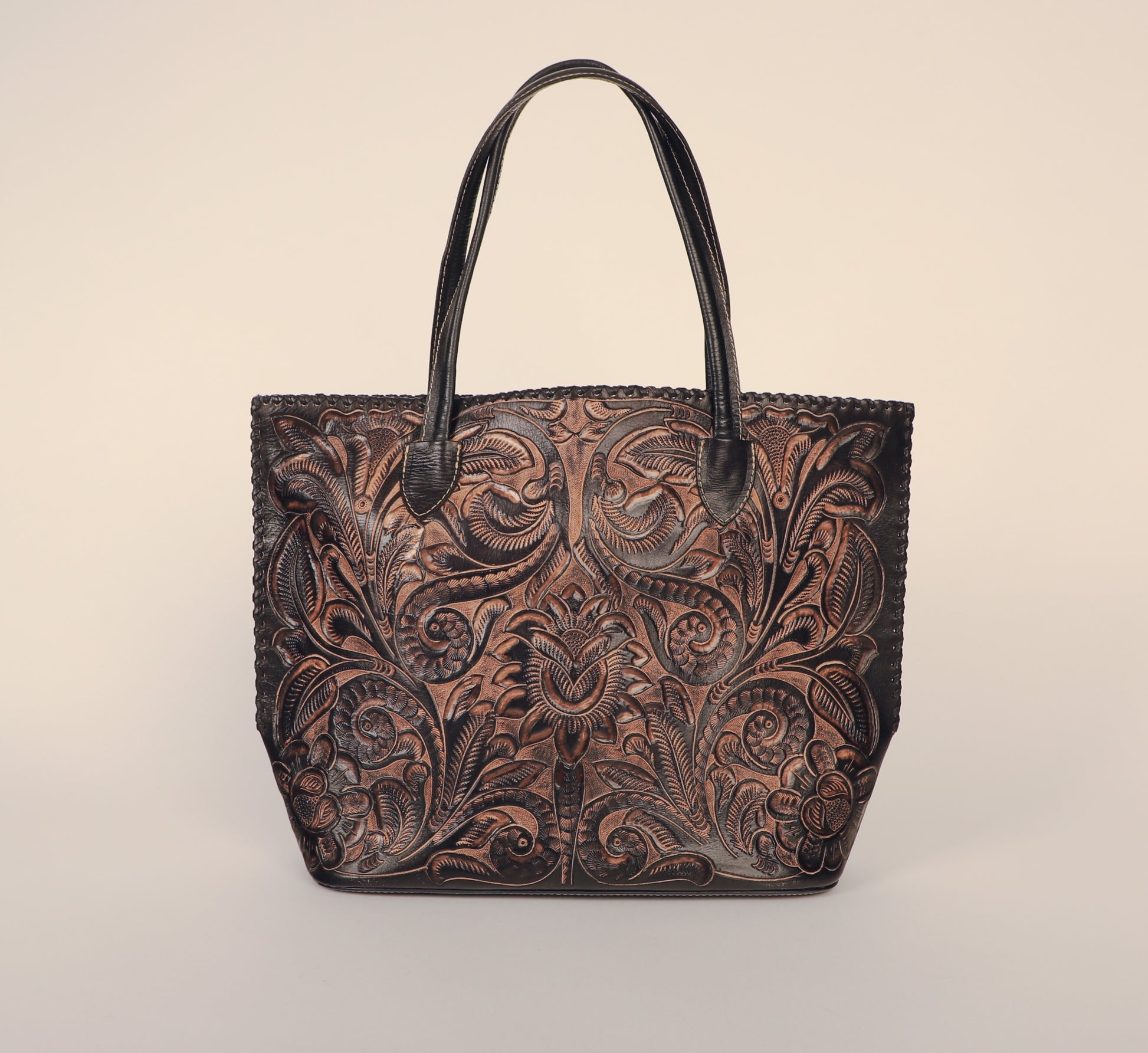 Over-sized authentic leather tote bag with traditional Mexican design etched on both sides. Fully lined with suede.  Front view with handles, dual colored black and brown.
