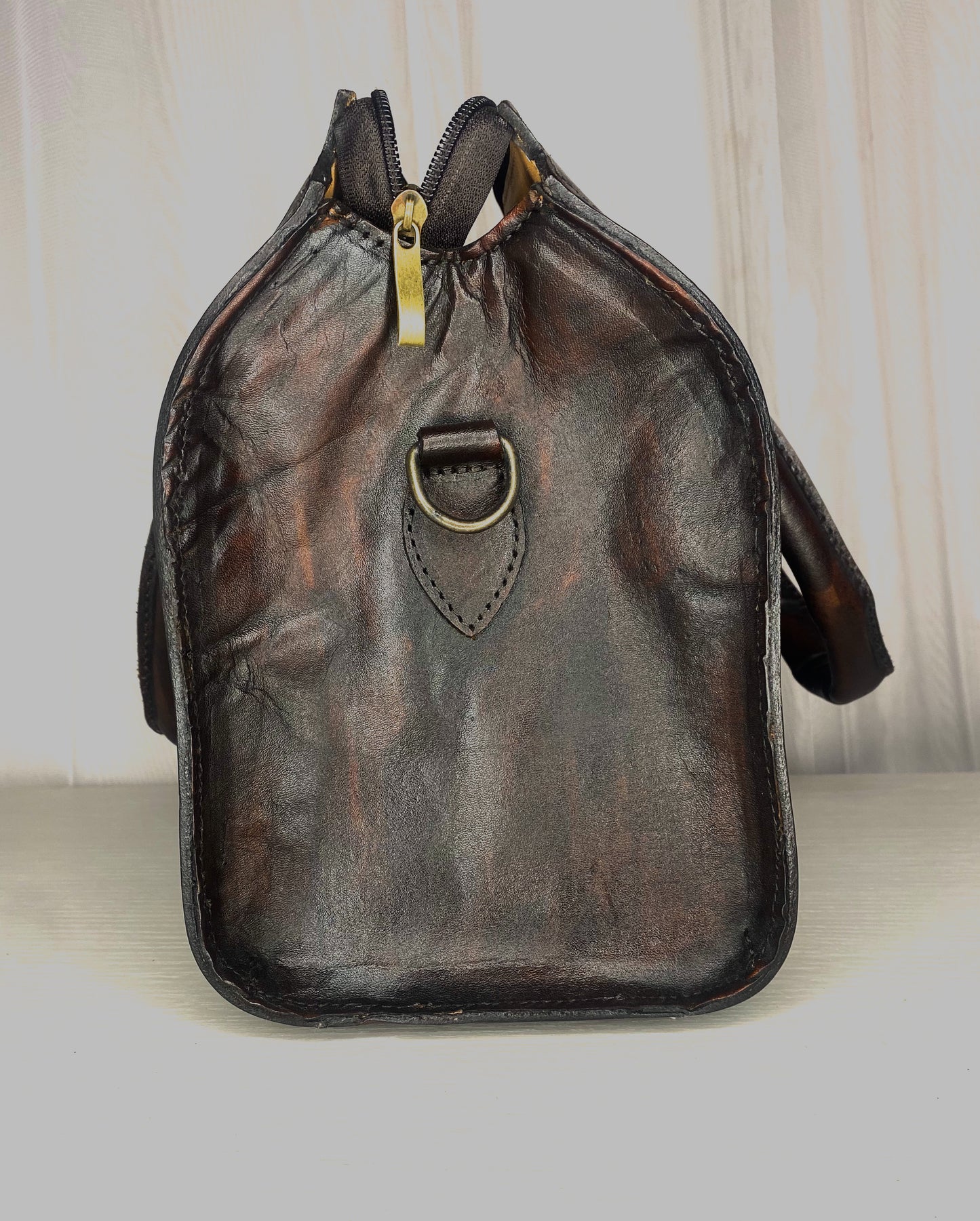 Medium sized bowling ball shaped authentic leather handbag. With strap to convert to crossbody, Mexican design etched throughout the bag, fully lined with suede. Side View in color vino