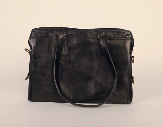 Medium-sized full leather messenger bag with one inch of traditional mexican Etching on the upper portion of the bag. Fully lined with suede.  Front view with handle hanging. 
