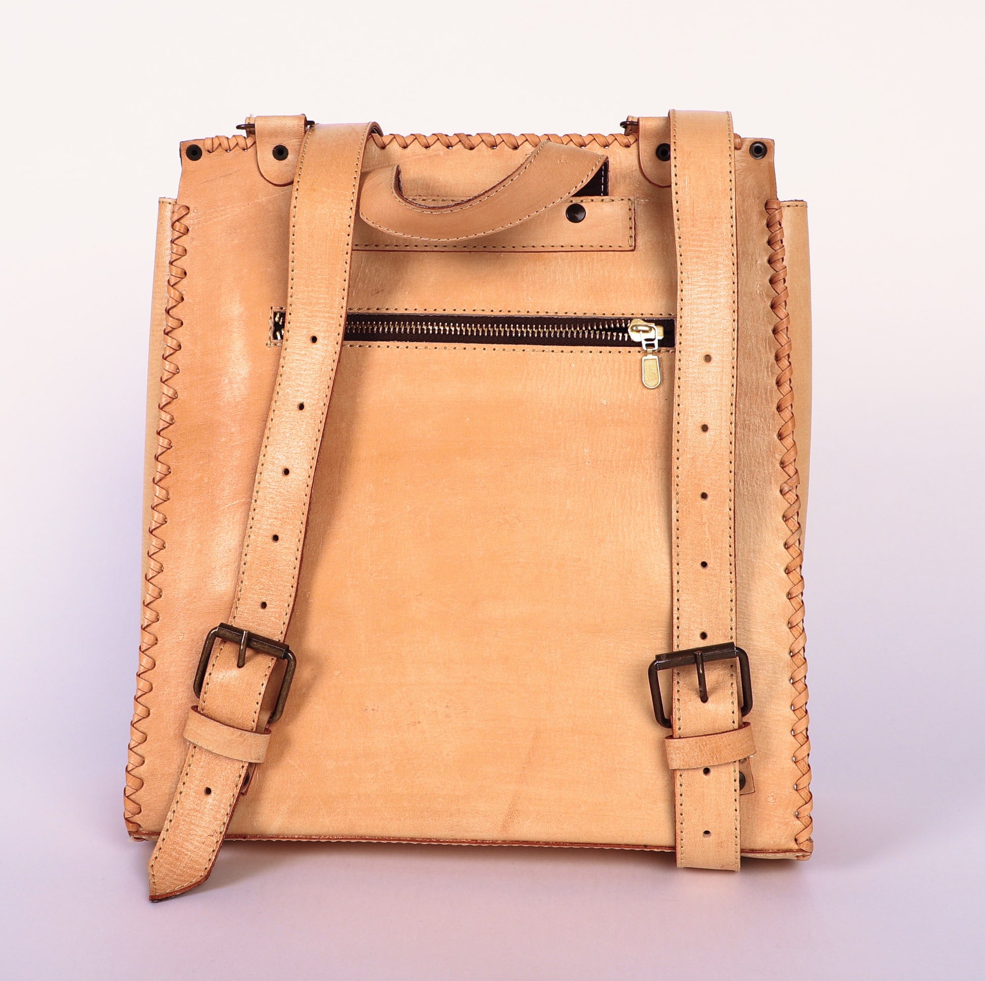 Traditional rectangle shaped Mexican backpack. Authentic leather in original nude color. Mexican Design etched only on  the top flap with buckle to close the flap.  Back view showing zipper pocket. Adjustable straps. 