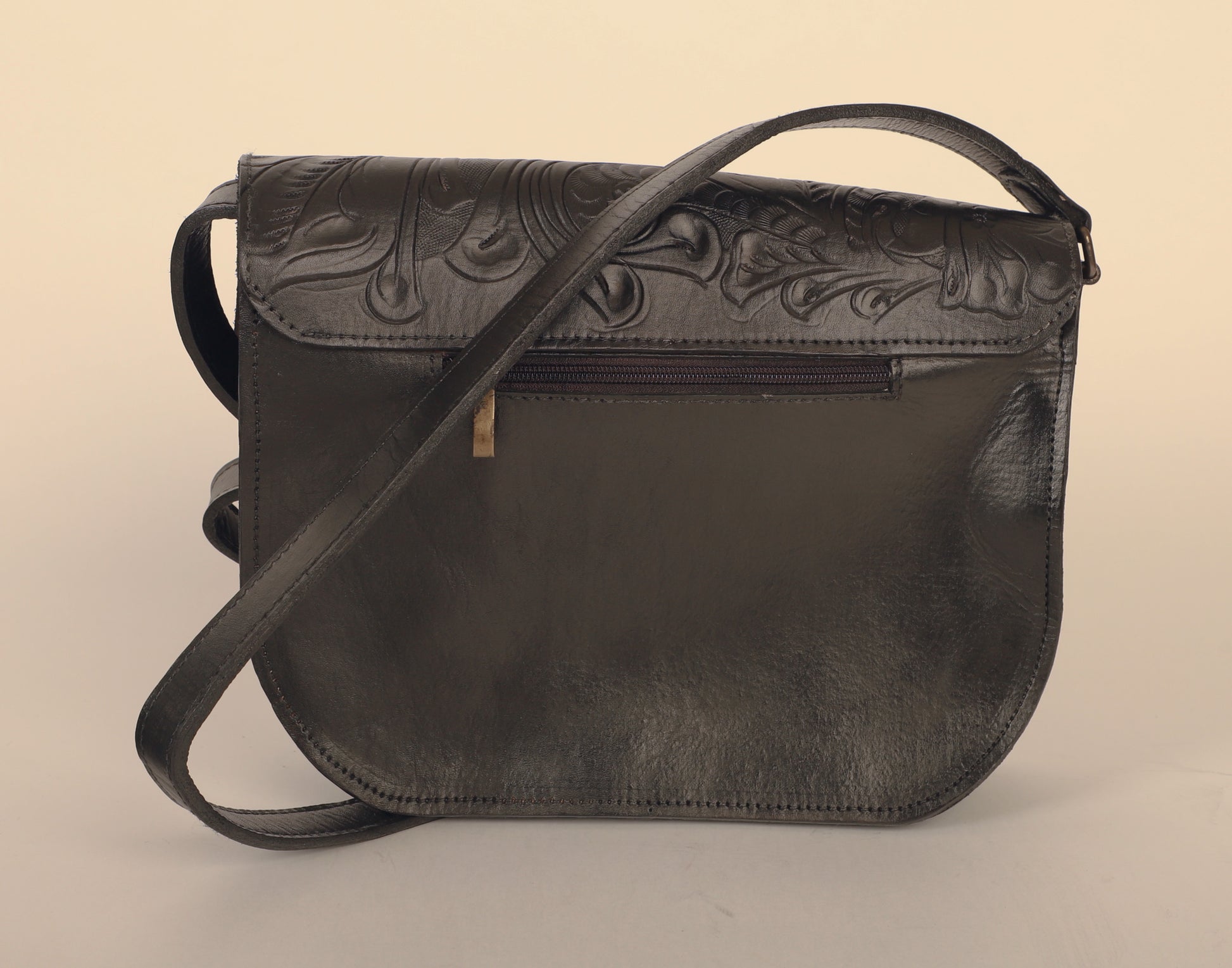 Larger-sized full leather crossbody bag with a rectangular shape and the unmistakenly mexican design on the outer flap. Fully lined with suede. In color black. Back view of the bag with the strap and back pocket. 