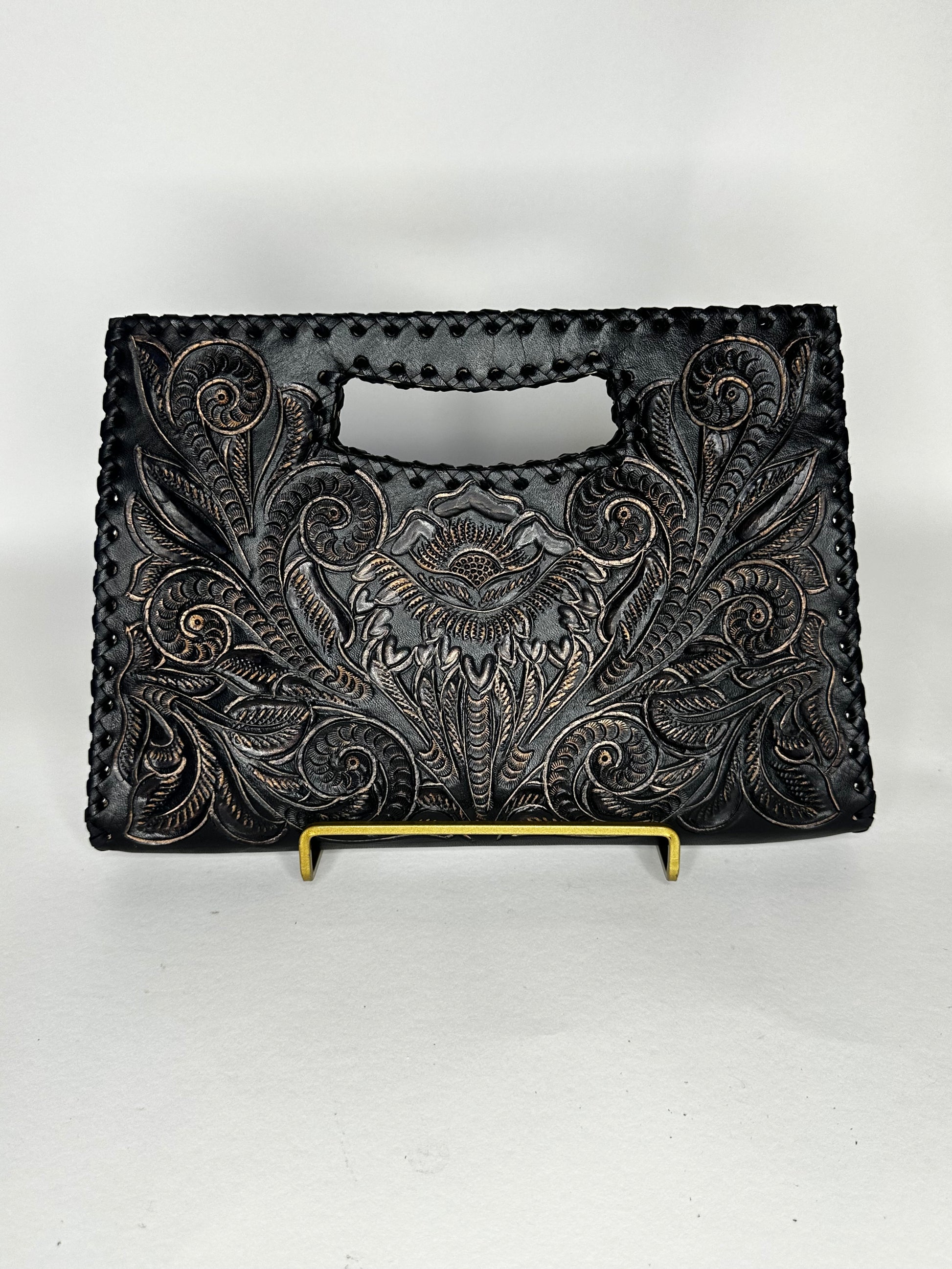 Small Mexican leather handbag with traditional design hand etched throughout the bag. Has handle mid top. leather stitching all around. Color black. 