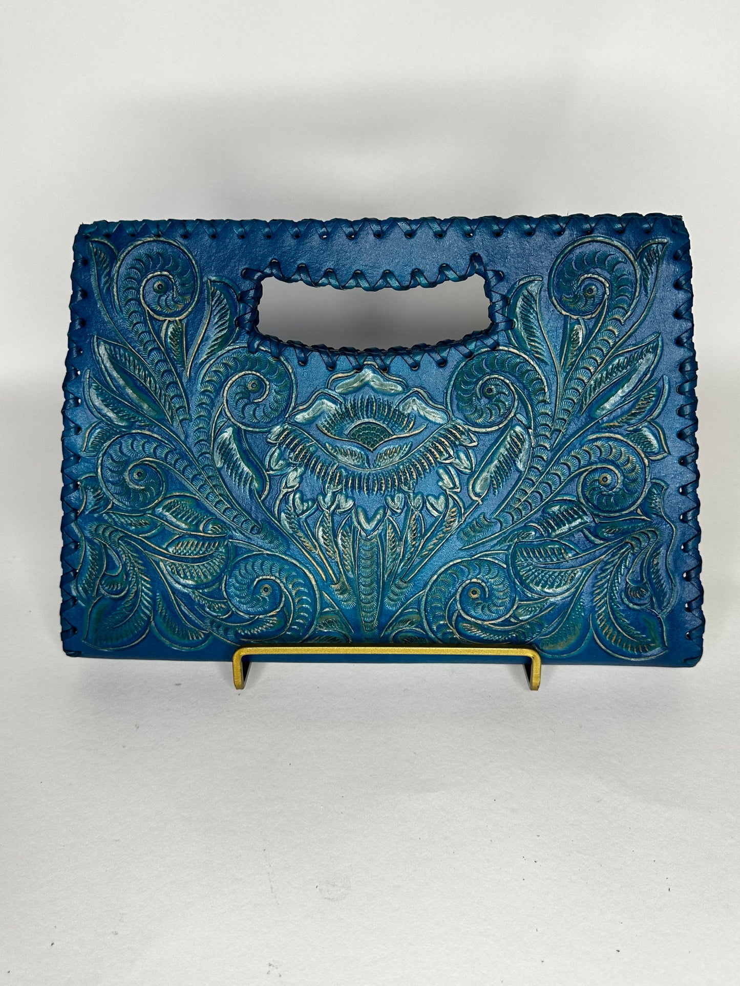 Small Mexican leather handbag with traditional design hand etched throughout the bag. Has handle mid top. leather stitching all around. Color ocean blue. 