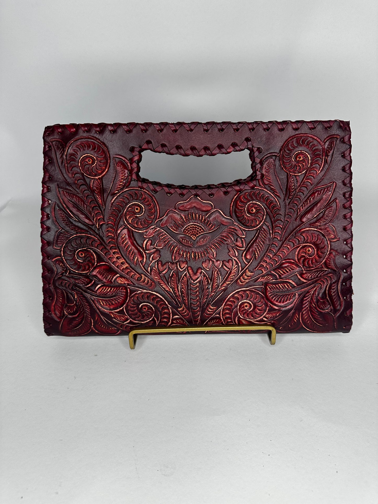 Small Mexican leather handbag with traditional design hand etched throughout the bag. Has handle mid top. leather stitching all around. Color wine red. 