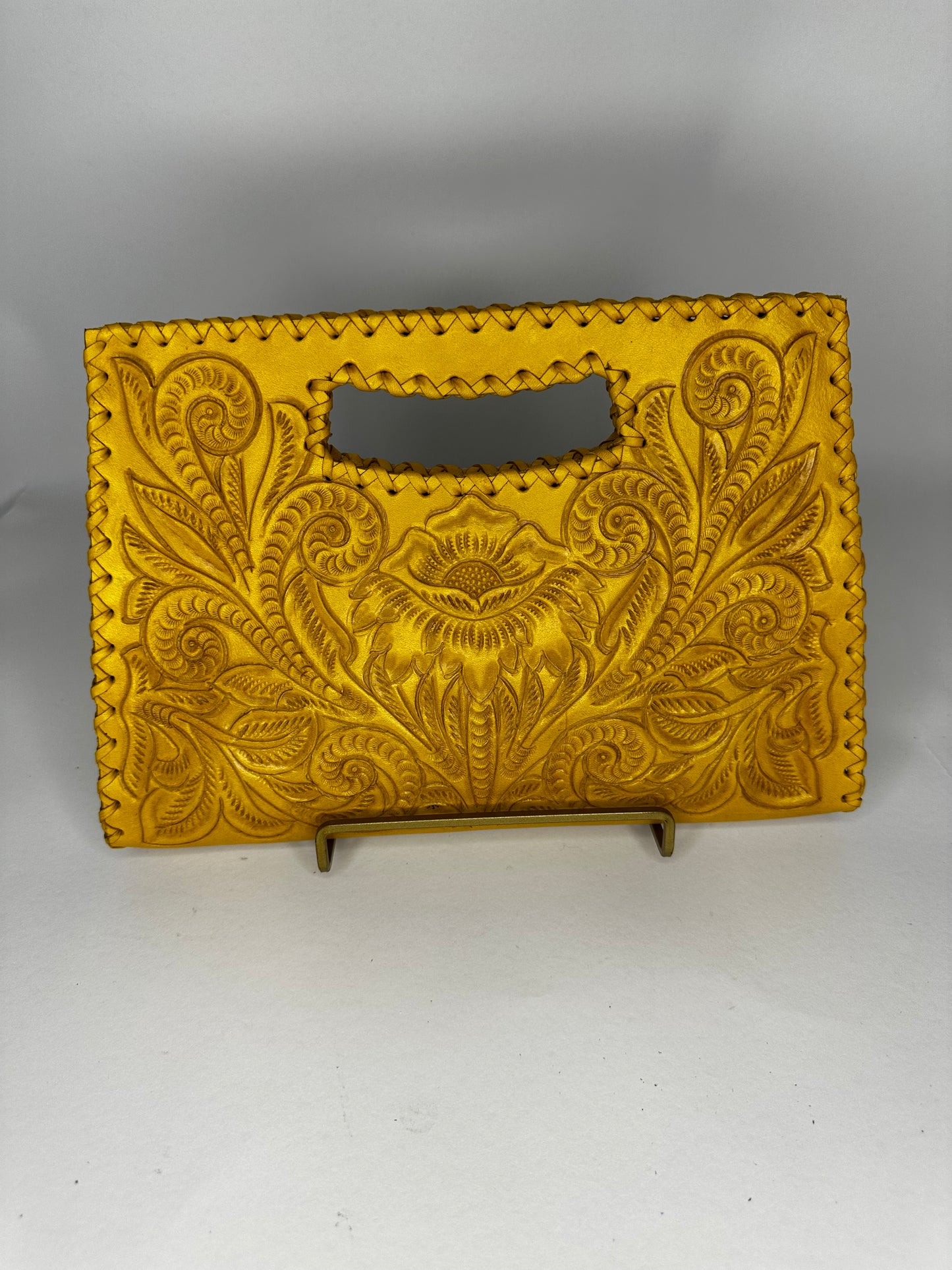 Small Mexican leather handbag with traditional design hand etched throughout the bag. Has handle mid top. leather stitching all around. Color mustard yellow.