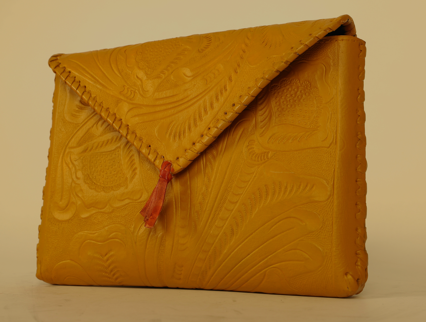 Small sized full leather crossbody bag with a triangular flap traditional mexican design on the outer flap of the purse. Fully lined with suede.  Front view in color yellow. 