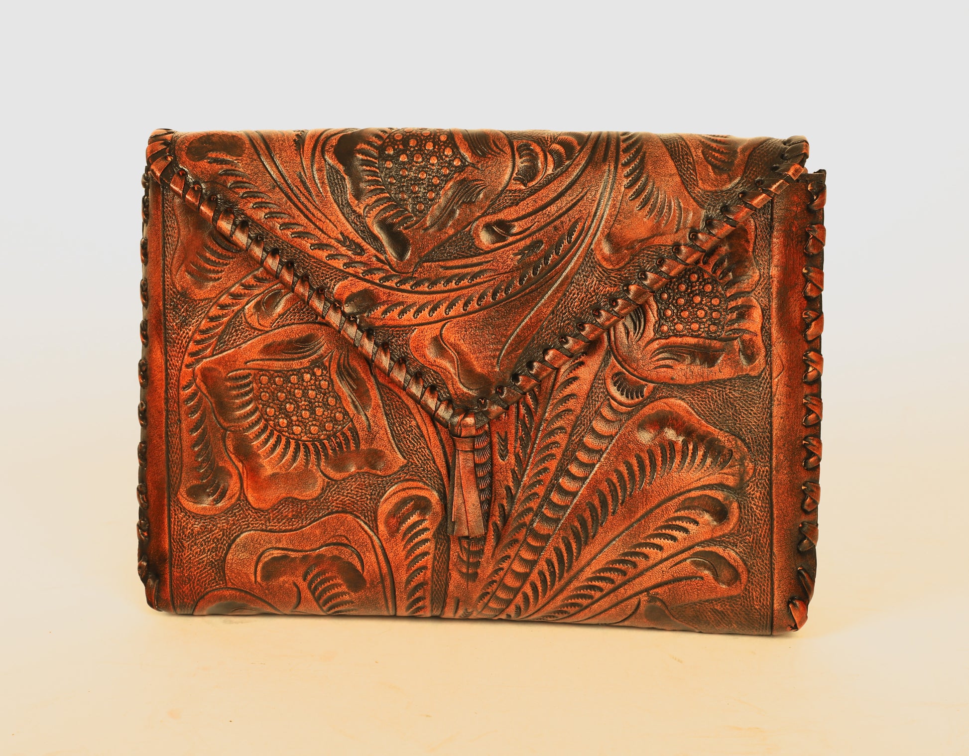 Small sized full leather crossbody bag with a triangular flap traditional mexican design on the outer flap of the purse. Fully lined with suede.  Front view of color brown fully etched clutch. 