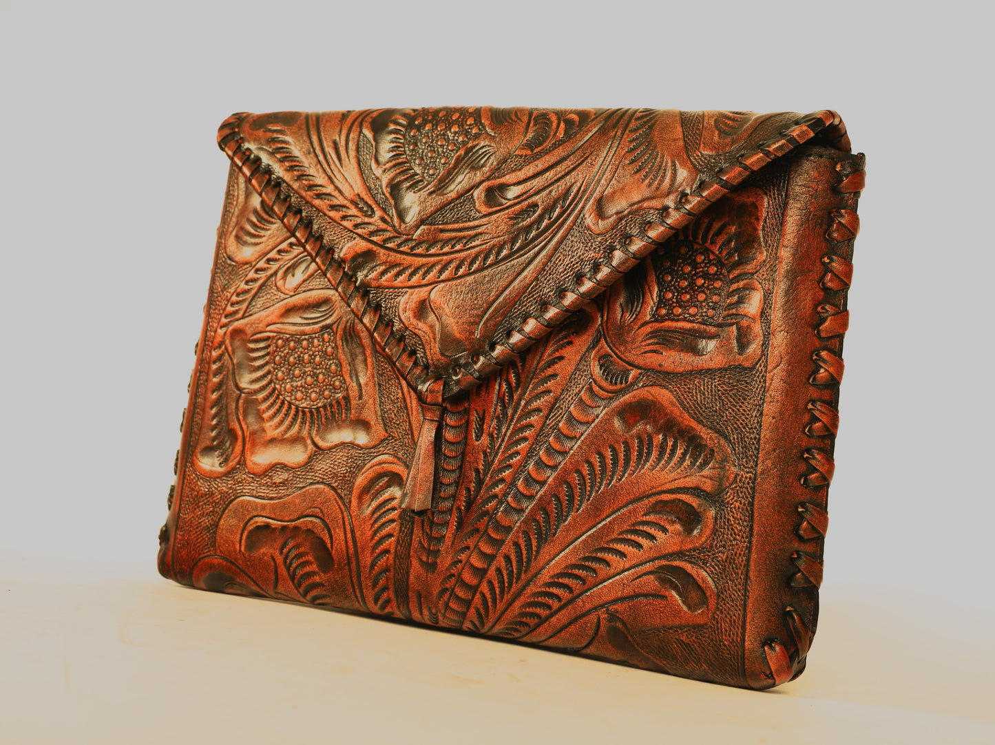 Small sized full leather crossbody bag with a triangular flap traditional mexican design on the outer flap of the purse. Fully lined with suede.  Front view of fully etched clutch. 